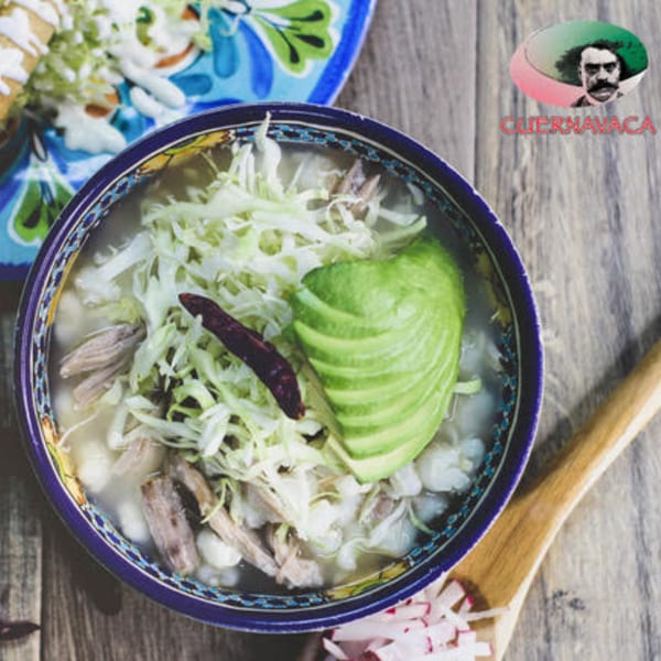 Pozole from Taqueria Cuernavaca, garnished with avocado, shredded cabbage, and a dried chili.