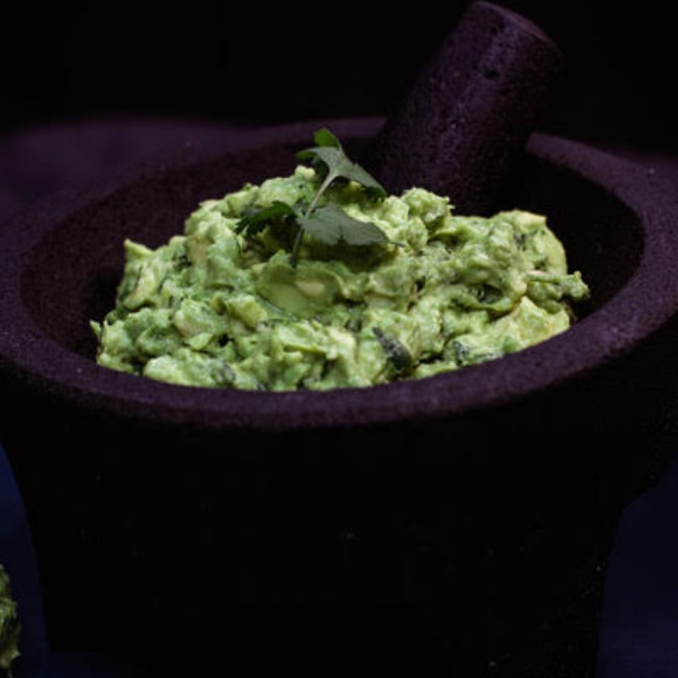 Freshly made guacamole with cilantro in a dark molcajete, ready to be served.